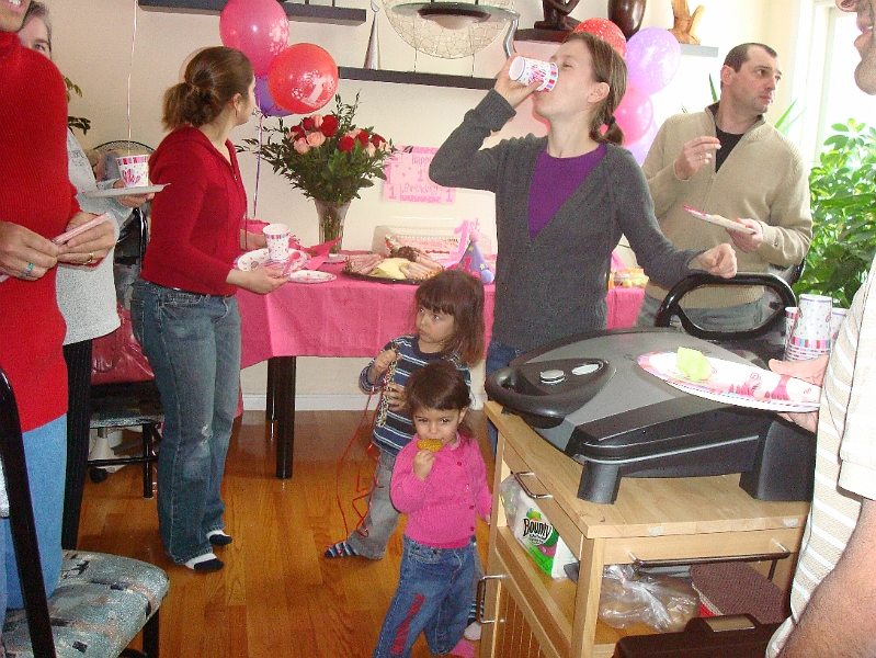 Bday-Valentine_0011.jpg - Anna imbibing in some refreshments with David and Mia in tow, while Oleg looks back in memory of his daughter's first birthday...or maybe he's just checking out the cupboards :-)  Hey, where's Luba??